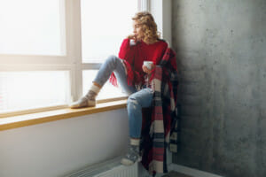 woman sat in window to keep warm in winter
